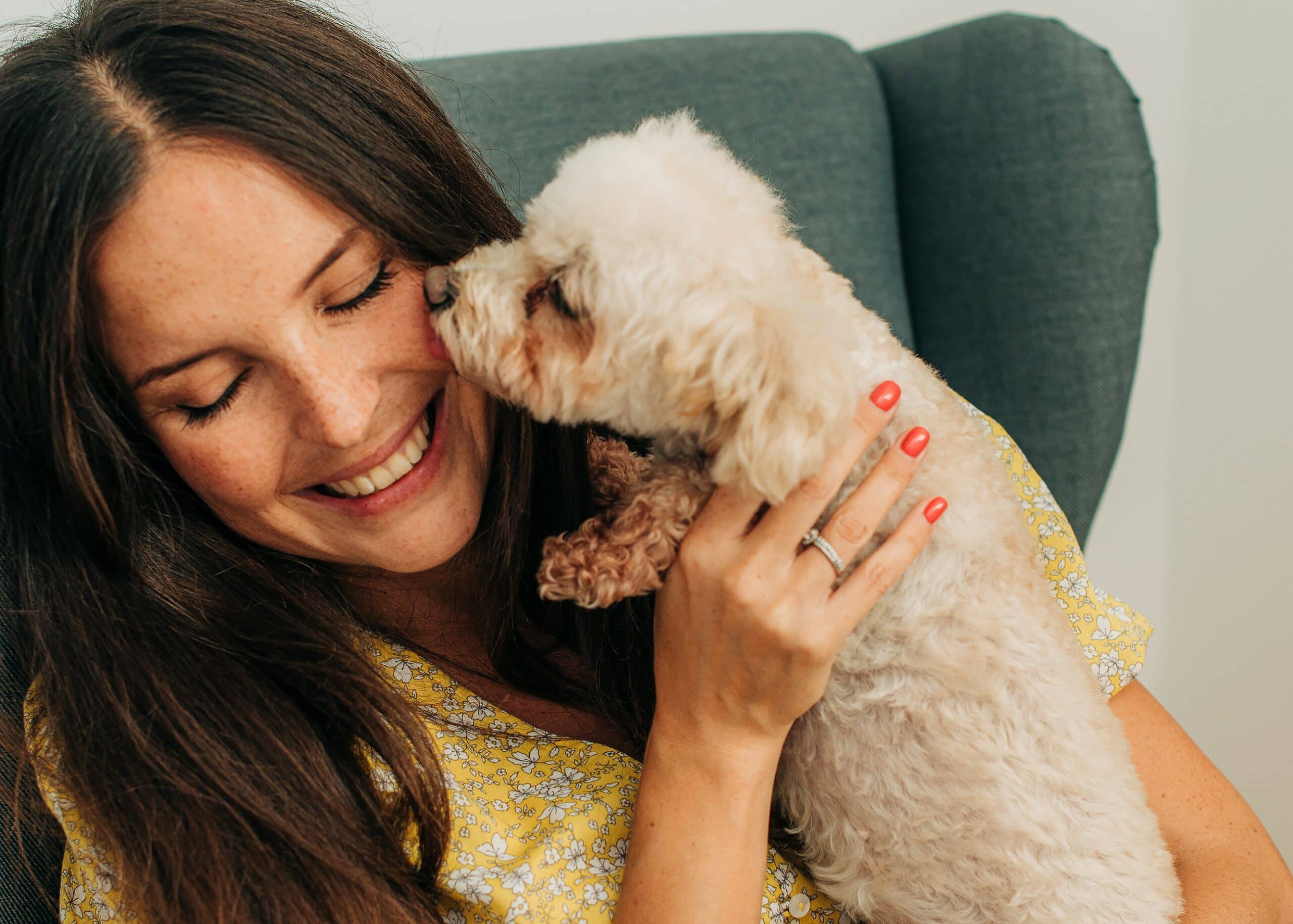 Woman being licked by a small white poodle